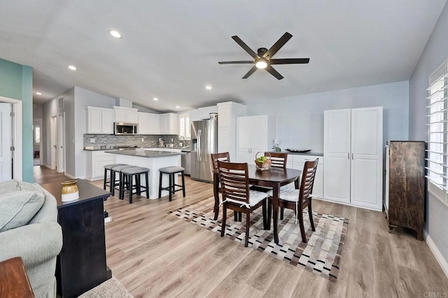 dining space with vaulted ceiling, ceiling fan, and light wood-type flooring