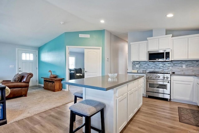 kitchen with stainless steel appliances, a kitchen breakfast bar, a center island, and white cabinets