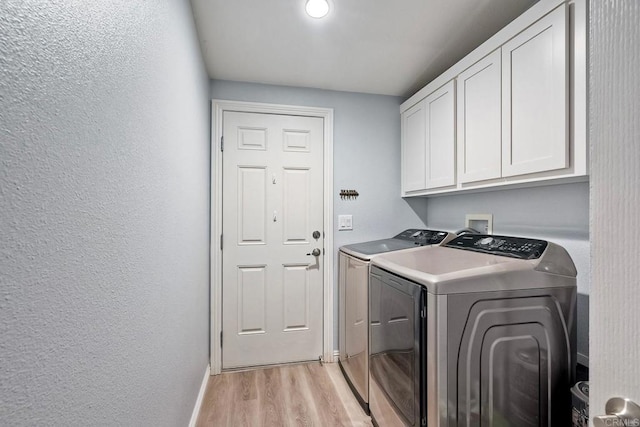 washroom featuring cabinets, washer and dryer, and light wood-type flooring