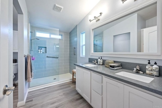 bathroom featuring wood-type flooring, a shower with shower door, vanity, and toilet