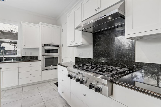 kitchen with sink, ornamental molding, appliances with stainless steel finishes, wall chimney range hood, and white cabinets