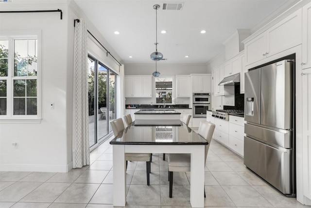 kitchen featuring white cabinetry, hanging light fixtures, light tile patterned floors, a kitchen island, and stainless steel appliances