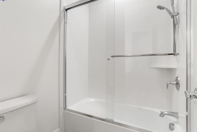 bathroom with bath / shower combo with glass door and toilet