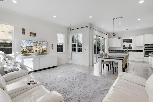 living room featuring crown molding, sink, and light tile patterned floors