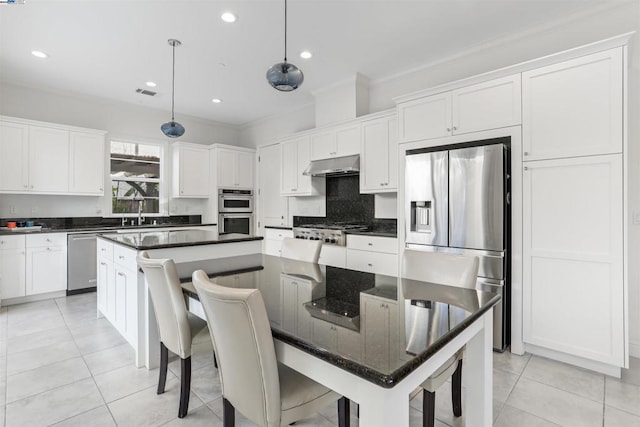 kitchen with hanging light fixtures, appliances with stainless steel finishes, white cabinets, and a kitchen island