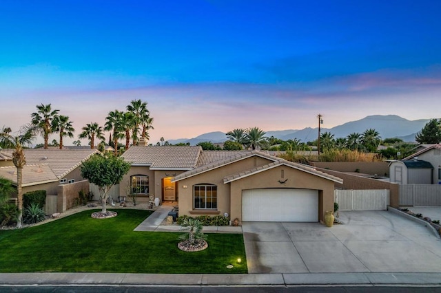 ranch-style house with a garage, a mountain view, and a yard