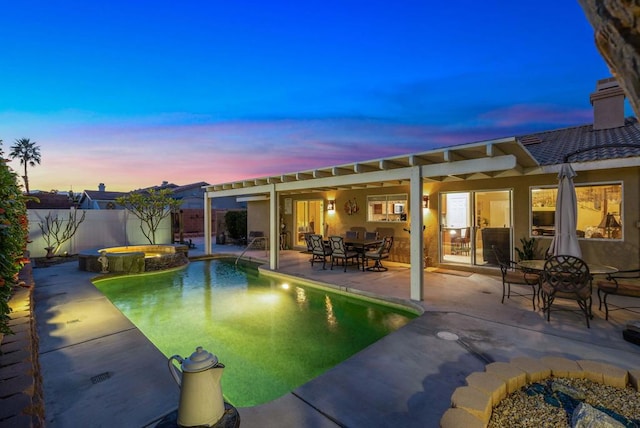 pool at dusk featuring a patio and an in ground hot tub