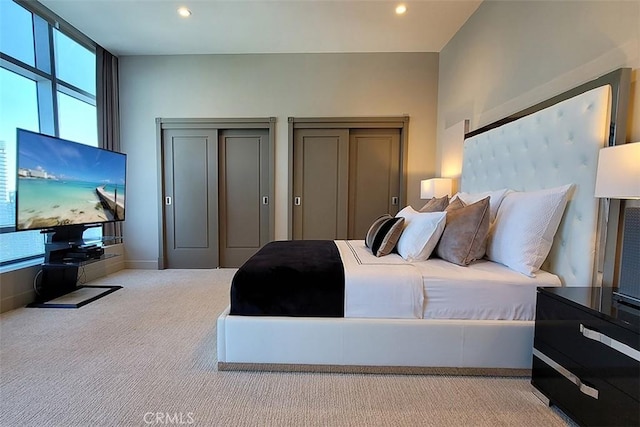 bedroom featuring light carpet and two closets