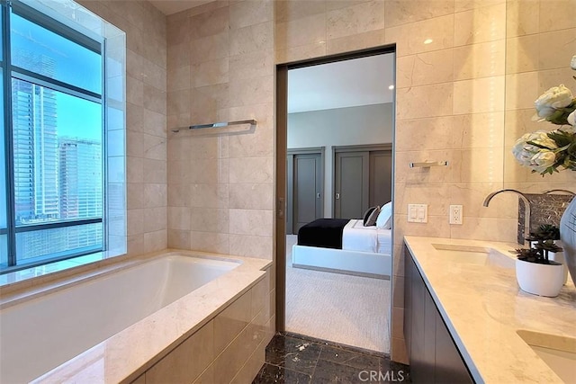 bathroom featuring tile walls, vanity, and tiled tub