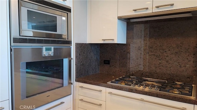 kitchen with white cabinetry, appliances with stainless steel finishes, extractor fan, and backsplash