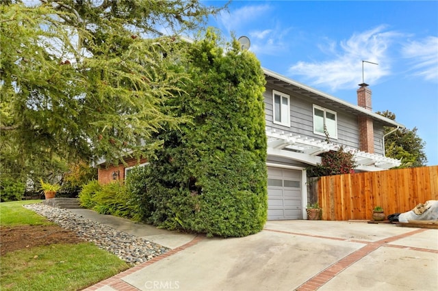obstructed view of property with an attached garage, a chimney, fence, and driveway