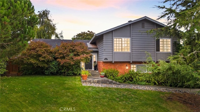 tri-level home featuring a front lawn and brick siding
