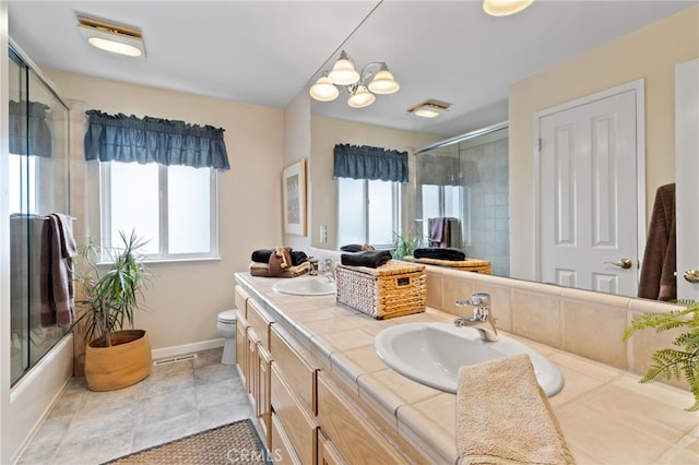 bathroom featuring enclosed tub / shower combo, toilet, a sink, and double vanity