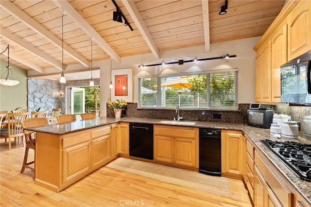 kitchen featuring sink, a breakfast bar area, decorative light fixtures, kitchen peninsula, and black appliances