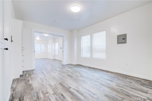 empty room featuring electric panel and light wood-type flooring