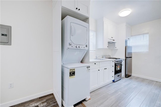 121/2 25th Pl, Venice, CA 90291 - laundry room featuring stacked washer / dryer, a sink, light wood-style floors, and baseboards