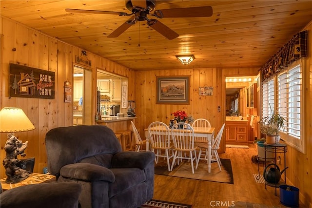 dining area with ceiling fan, wood walls, wood-type flooring, and wooden ceiling