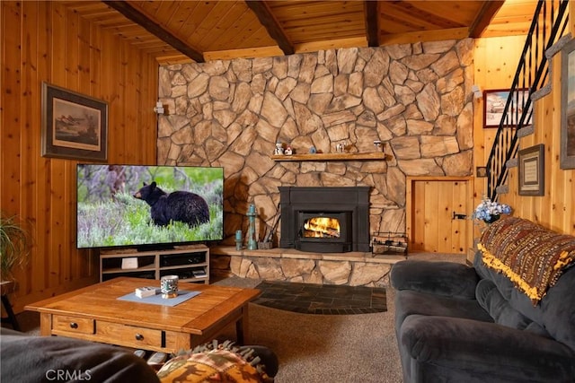 carpeted living room featuring beam ceiling, a fireplace, wooden ceiling, and wooden walls