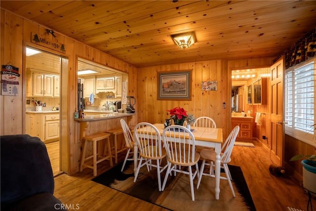 dining space with wood ceiling, light hardwood / wood-style floors, and wood walls