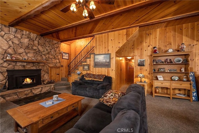 carpeted living room featuring ceiling fan, beam ceiling, a fireplace, wooden ceiling, and wood walls