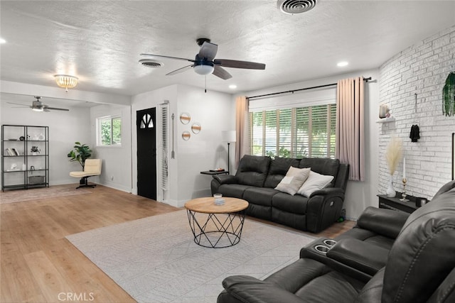 living room featuring ceiling fan, a healthy amount of sunlight, a textured ceiling, and light hardwood / wood-style flooring