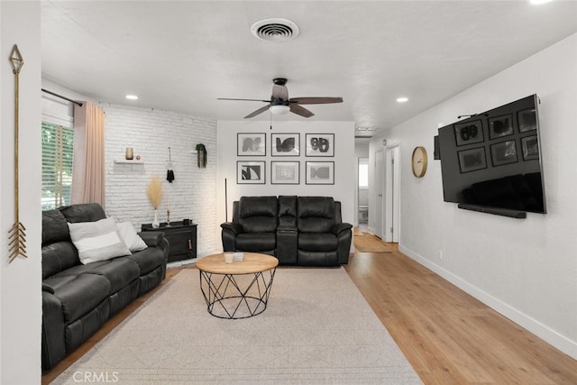 living room with ceiling fan, light wood-type flooring, a healthy amount of sunlight, and a wood stove