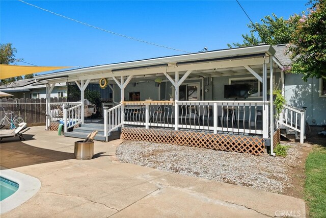 rear view of property featuring a wooden deck and a patio