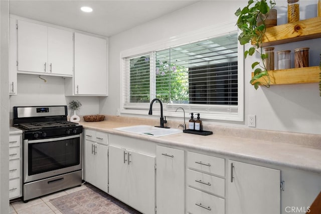 kitchen featuring light tile patterned flooring, sink, gas stove, and white cabinets