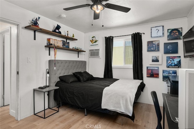 bedroom with ceiling fan, a wall mounted air conditioner, and light hardwood / wood-style floors