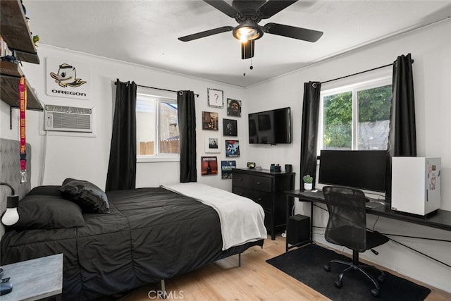 bedroom with ornamental molding, a wall unit AC, ceiling fan, and light wood-type flooring