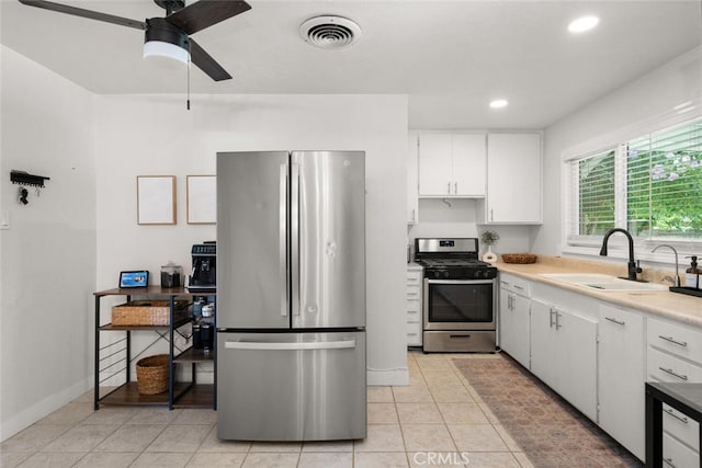 kitchen featuring stainless steel appliances, light tile patterned flooring, sink, and white cabinets