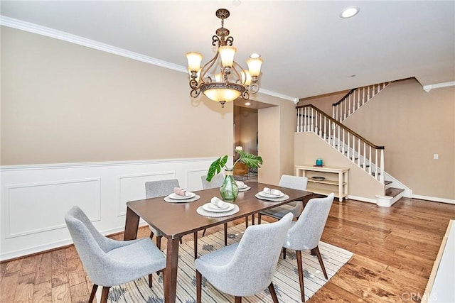 dining area featuring hardwood / wood-style flooring, crown molding, and an inviting chandelier