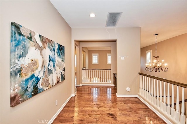 hall with hardwood / wood-style floors and a notable chandelier