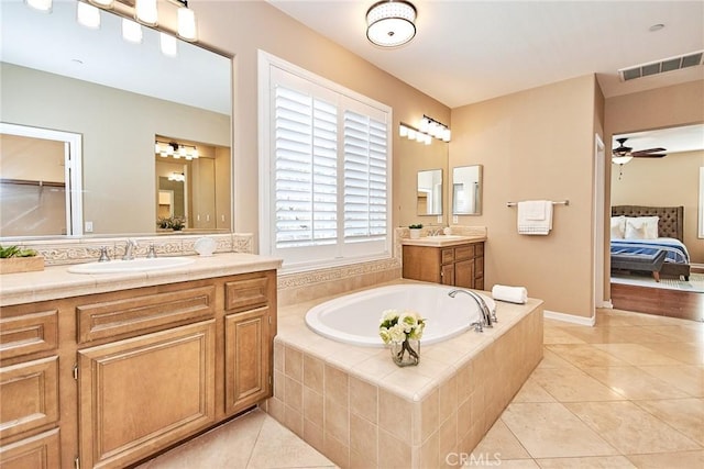 bathroom with tile patterned flooring, vanity, a relaxing tiled tub, and ceiling fan