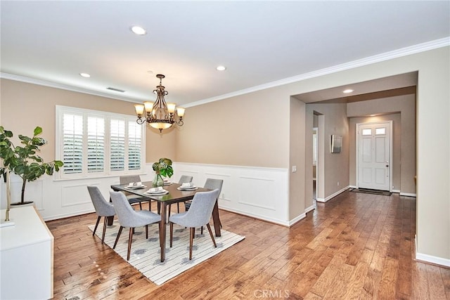 dining room featuring a notable chandelier, light hardwood / wood-style flooring, and ornamental molding