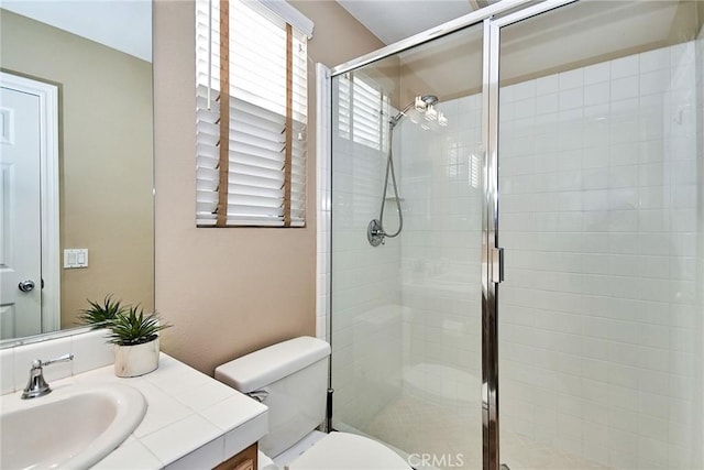 bathroom featuring a shower with door, vanity, and toilet