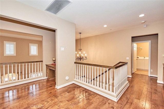 hallway featuring hardwood / wood-style flooring and a chandelier