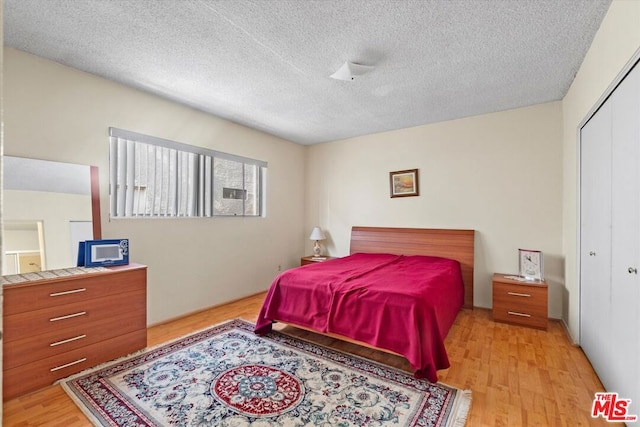 bedroom with a closet, light hardwood / wood-style flooring, and a textured ceiling