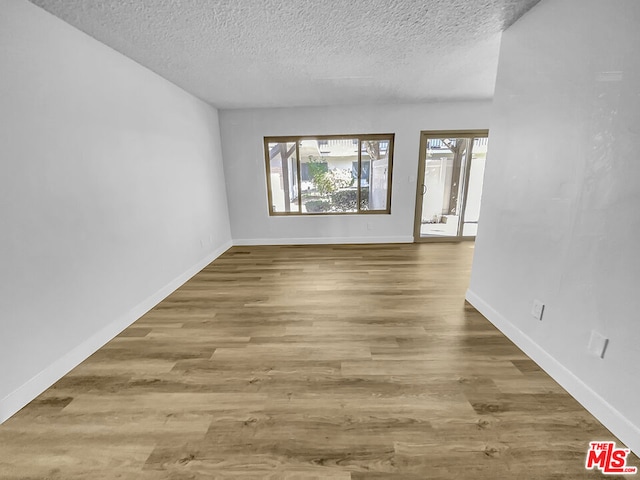 empty room with hardwood / wood-style floors and a textured ceiling