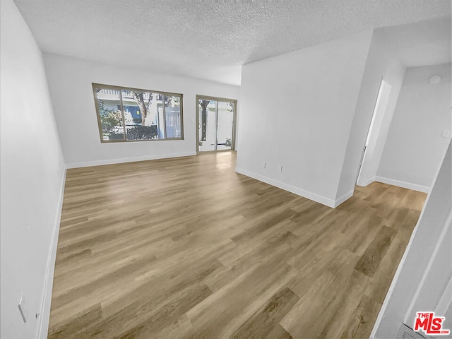 unfurnished living room featuring hardwood / wood-style floors and a textured ceiling