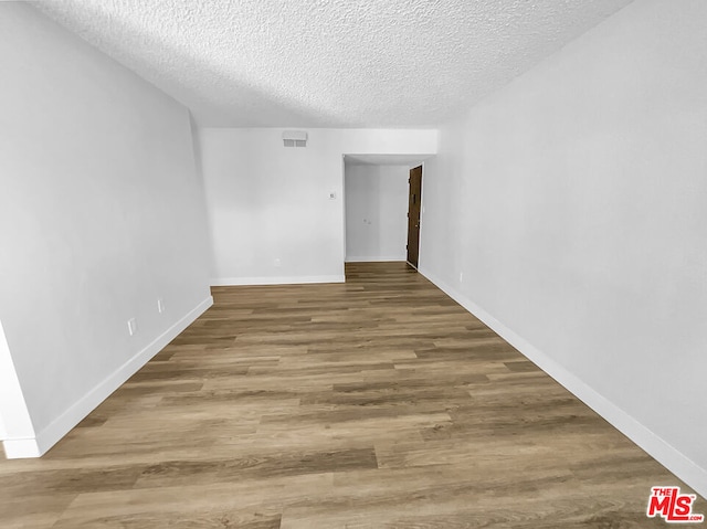 unfurnished room with hardwood / wood-style flooring and a textured ceiling