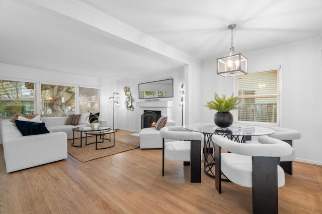 living room with a notable chandelier, crown molding, a fireplace, and light hardwood / wood-style floors