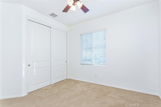 unfurnished bedroom featuring light colored carpet, ceiling fan, and a closet