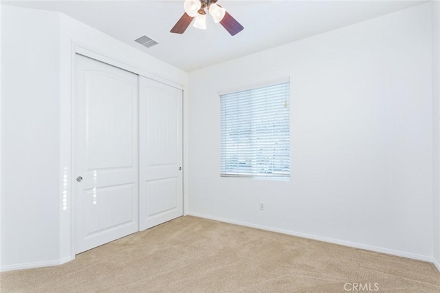 unfurnished bedroom with a closet, visible vents, light carpet, and baseboards