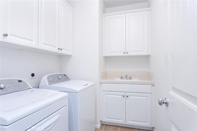 laundry room with cabinets, washing machine and clothes dryer, and sink