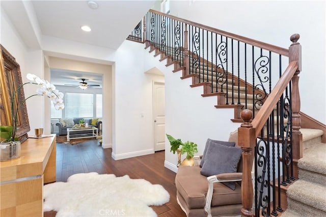 stairs with wood-type flooring and ceiling fan