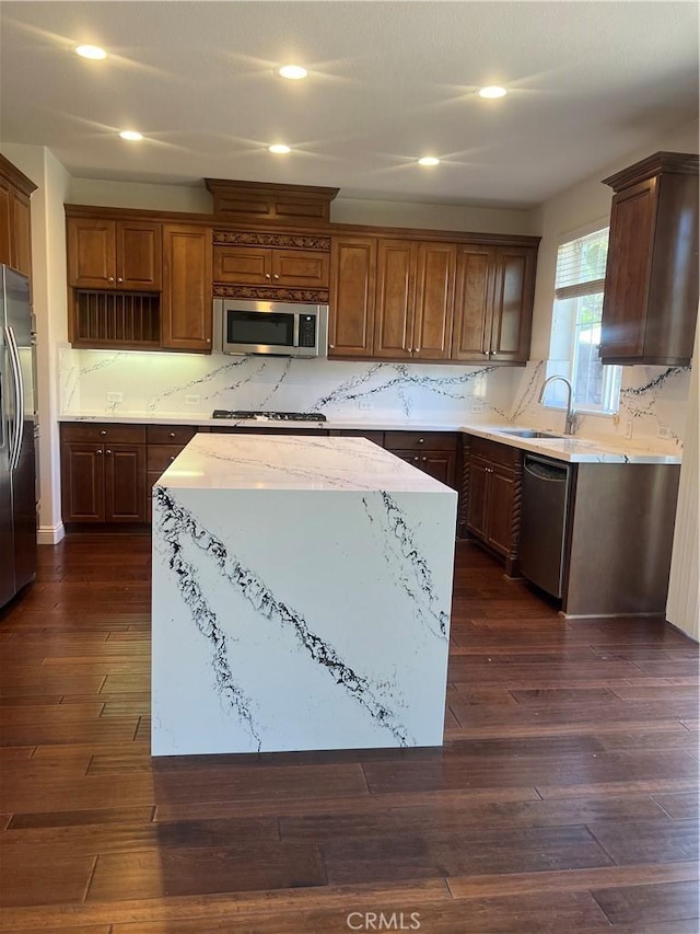 kitchen featuring stainless steel appliances, a kitchen island, a sink, and dark wood finished floors