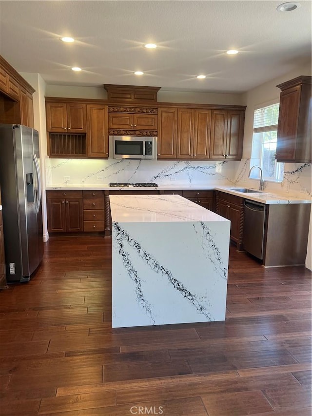 kitchen featuring appliances with stainless steel finishes, dark wood-type flooring, a kitchen island, and a sink