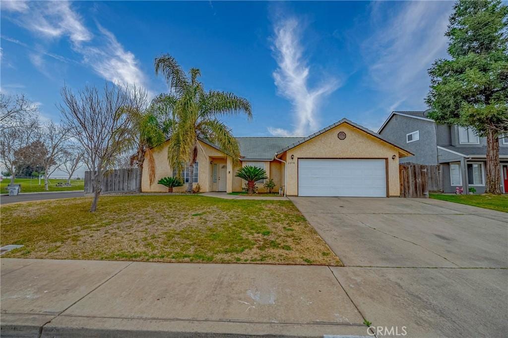 single story home featuring concrete driveway, a front lawn, fence, and stucco siding