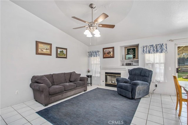 tiled living room with a tile fireplace, vaulted ceiling, and ceiling fan